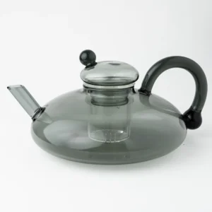Bule de vidro cinza fumê com infusor integrado e alça em arco, ideal para preparo de chás em folhas com visual moderno e elegante